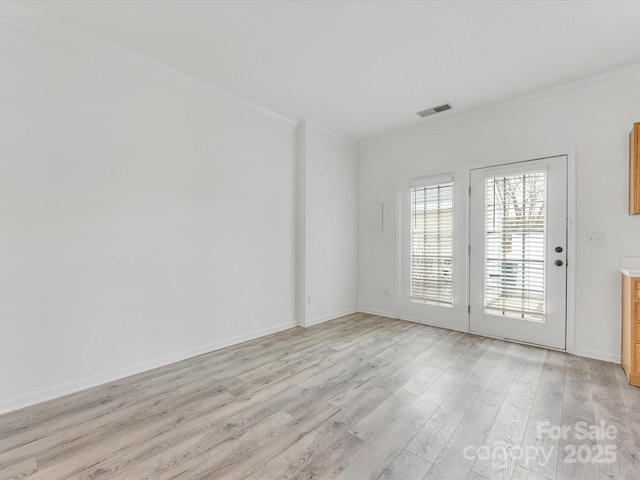 spare room with visible vents, crown molding, light wood-type flooring, and baseboards