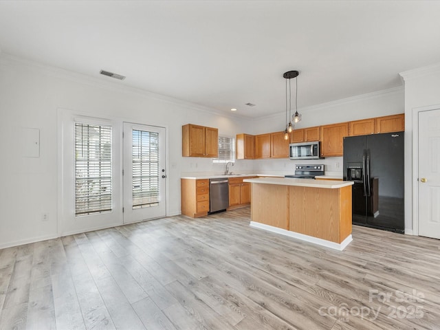 kitchen featuring light wood finished floors, visible vents, a kitchen island, light countertops, and appliances with stainless steel finishes