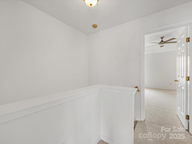 corridor with an upstairs landing and light colored carpet