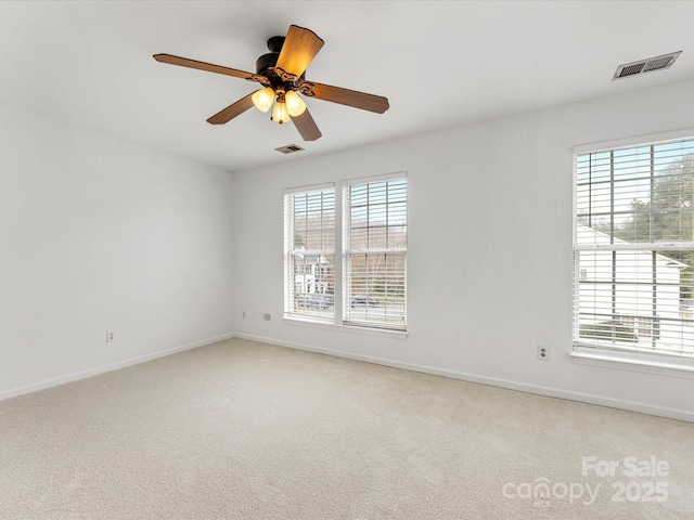 empty room featuring visible vents, light carpet, and plenty of natural light