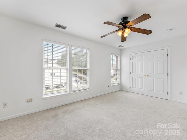 unfurnished bedroom featuring multiple windows, carpet, visible vents, and baseboards