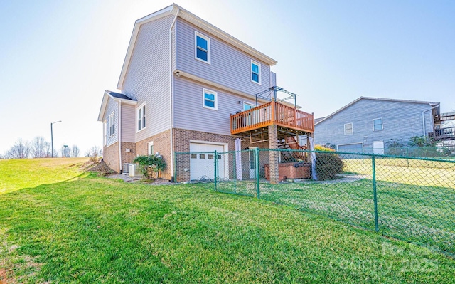 rear view of house with brick siding, fence, a garage, a deck, and a yard