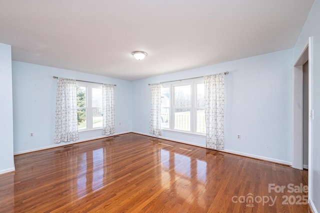 spare room featuring visible vents, baseboards, and wood finished floors