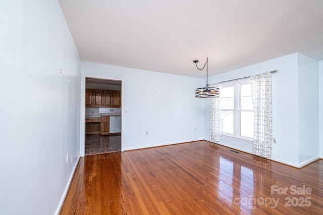 interior space featuring visible vents, baseboards, an inviting chandelier, and wood finished floors