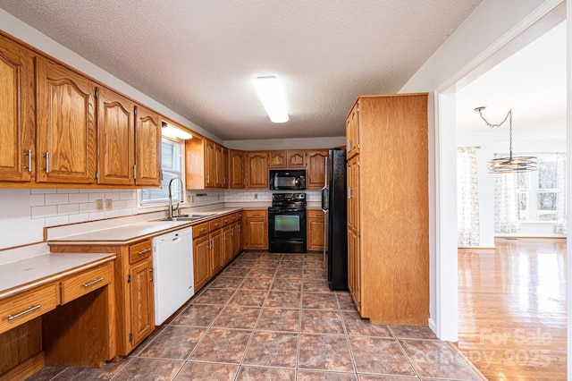 kitchen with tasteful backsplash, light countertops, brown cabinets, black appliances, and a sink