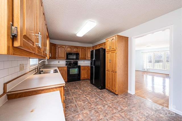 kitchen with plenty of natural light, black appliances, light countertops, and a sink