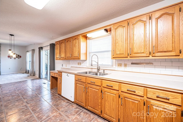 kitchen featuring backsplash, white dishwasher, a wealth of natural light, and a sink