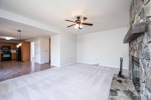 unfurnished living room featuring baseboards, dark carpet, a fireplace, a textured ceiling, and a ceiling fan