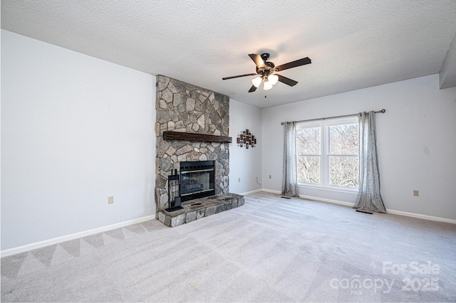 unfurnished living room with a stone fireplace, baseboards, carpet floors, and ceiling fan