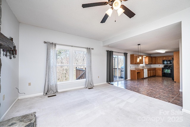 unfurnished living room featuring visible vents, baseboards, dark colored carpet, a ceiling fan, and dark tile patterned flooring