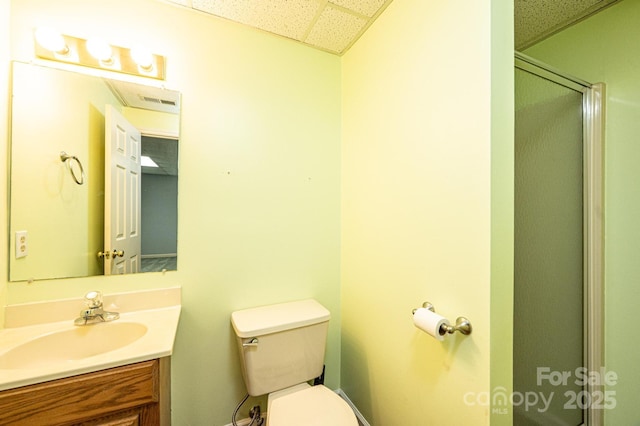 full bathroom featuring a drop ceiling, an enclosed shower, toilet, and vanity