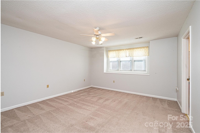 spare room featuring light carpet, visible vents, baseboards, and ceiling fan