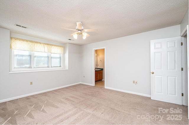 unfurnished bedroom featuring visible vents, baseboards, ensuite bathroom, and carpet flooring