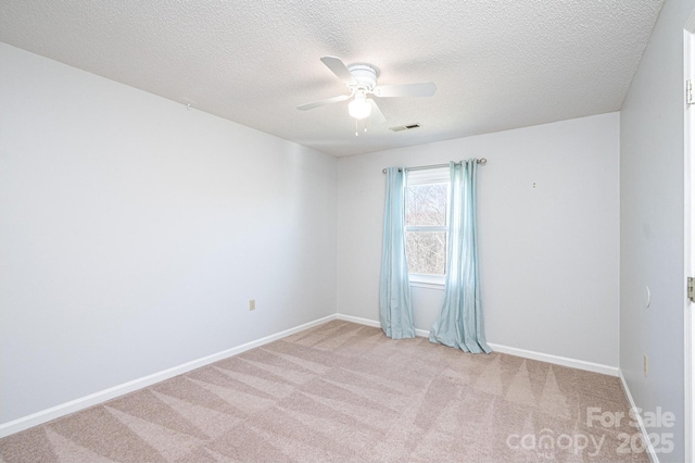 carpeted spare room with visible vents, a textured ceiling, baseboards, and ceiling fan