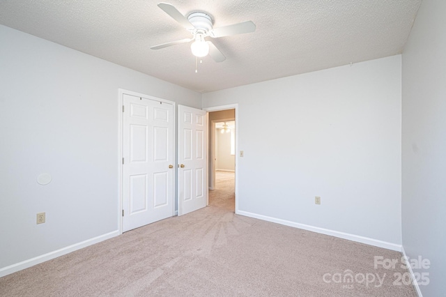 unfurnished bedroom with baseboards, carpet, a ceiling fan, and a textured ceiling