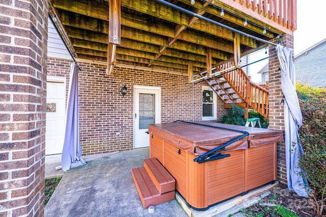 view of patio featuring stairway and a hot tub