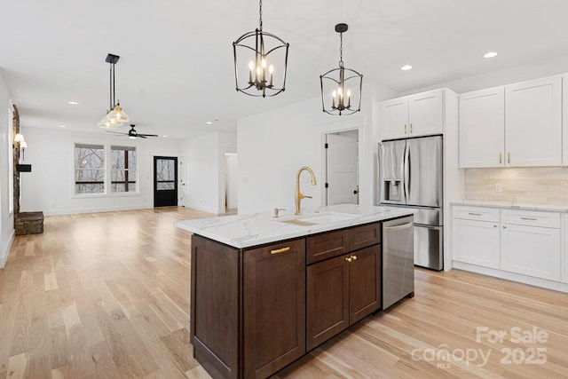 kitchen with a sink, dark brown cabinetry, white cabinets, appliances with stainless steel finishes, and tasteful backsplash