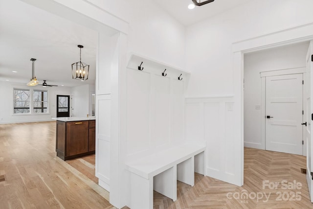 mudroom with ceiling fan with notable chandelier, recessed lighting, wainscoting, a decorative wall, and parquet flooring