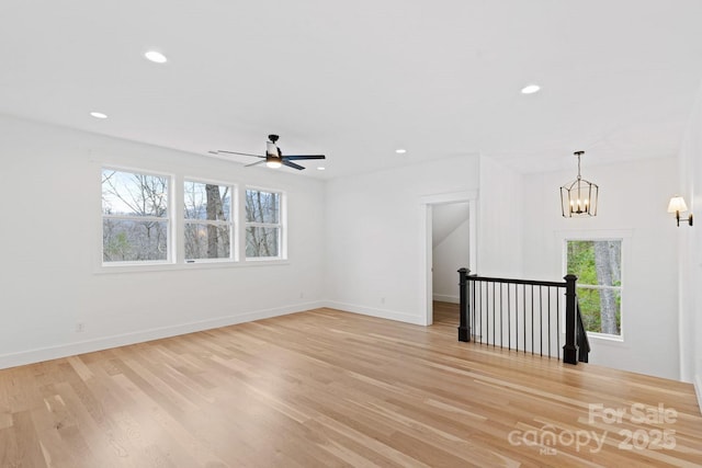 spare room featuring ceiling fan with notable chandelier, light wood-style flooring, recessed lighting, and baseboards