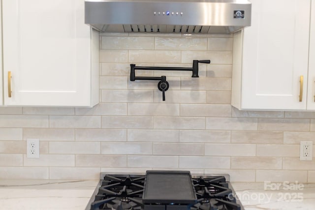 details featuring backsplash, white cabinetry, and wall chimney range hood