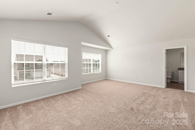 empty room with lofted ceiling, carpet flooring, baseboards, and visible vents