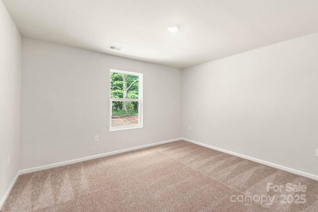 carpeted spare room featuring baseboards and visible vents