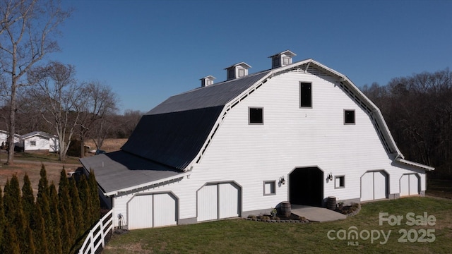 view of side of home with a barn, a lawn, a gambrel roof, and an outdoor structure