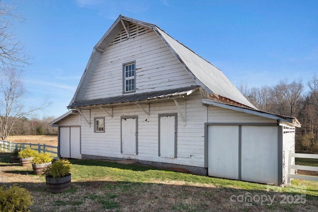 rear view of property with a gambrel roof, metal roof, a yard, and fence