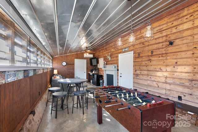 recreation room with wooden walls, concrete floors, and vaulted ceiling