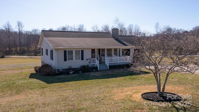 view of front facade featuring fence, roof with shingles, a porch, a chimney, and a front lawn