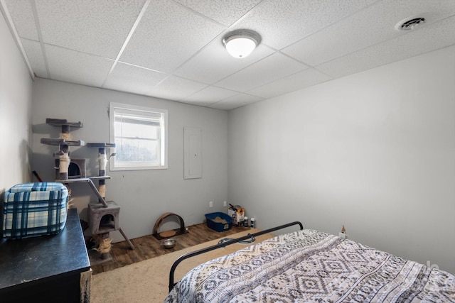 bedroom with electric panel, visible vents, a paneled ceiling, and wood finished floors