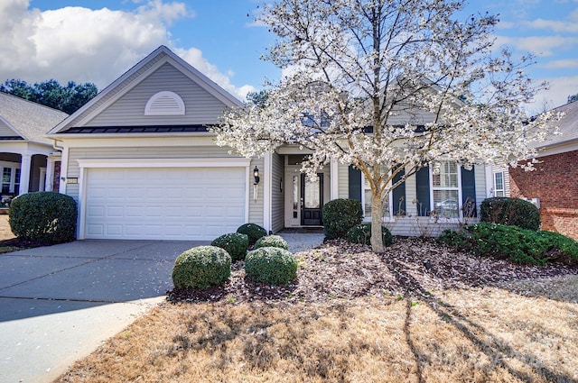 view of front of home featuring metal roof, a garage, driveway, and a standing seam roof