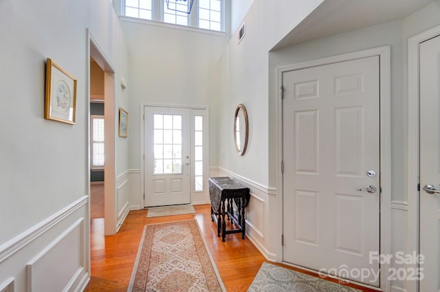 foyer with visible vents, wainscoting, and light wood-style floors