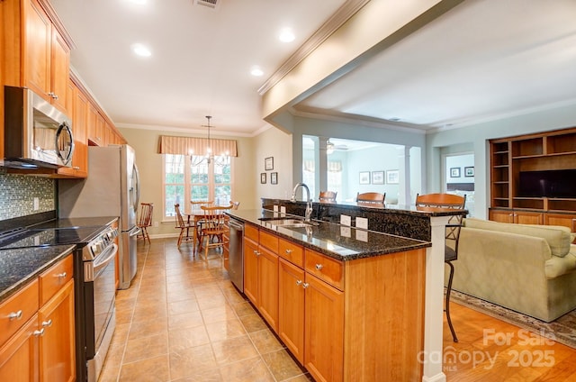 kitchen with a sink, appliances with stainless steel finishes, a kitchen breakfast bar, open floor plan, and backsplash