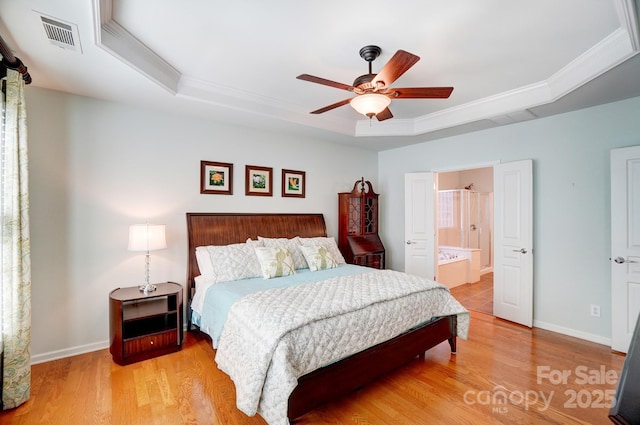 bedroom featuring visible vents, a tray ceiling, light wood-style floors, crown molding, and baseboards