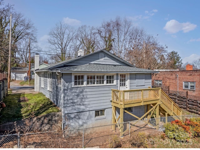 back of house with a wooden deck, stairs, roof with shingles, and fence