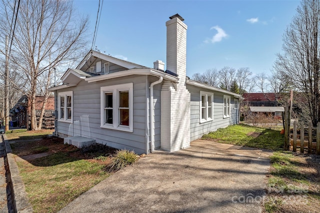 view of side of home featuring a yard, fence, and a chimney