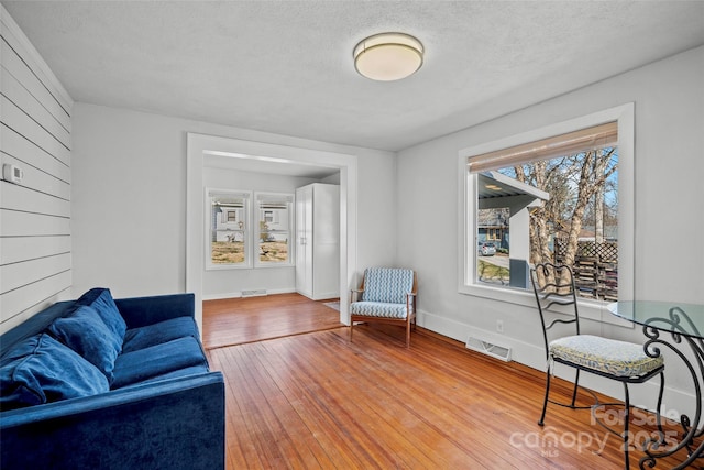 sitting room featuring visible vents, wood-type flooring, a textured ceiling, and baseboards