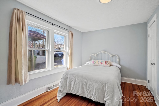 bedroom featuring wood finished floors, visible vents, and baseboards