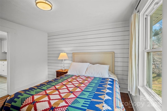 bedroom with baseboards, wooden walls, and wood finished floors