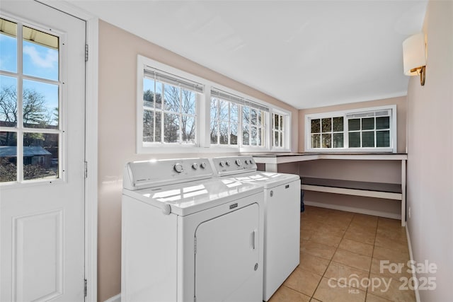 clothes washing area featuring washer and clothes dryer, laundry area, baseboards, and light tile patterned flooring