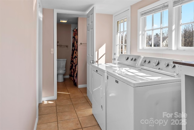 laundry room featuring light tile patterned floors, washing machine and dryer, and baseboards