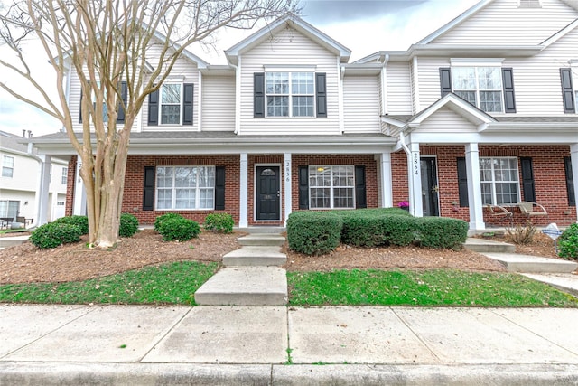 multi unit property with brick siding and a porch