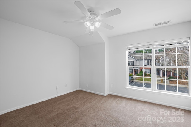 unfurnished room with visible vents, baseboards, vaulted ceiling, carpet floors, and a ceiling fan