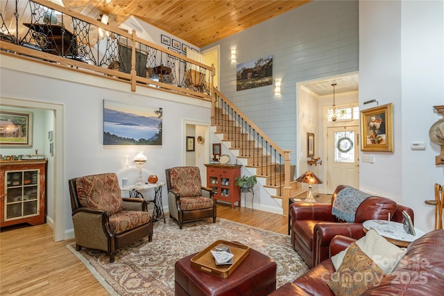 living room with stairway, a high ceiling, a notable chandelier, and wood finished floors