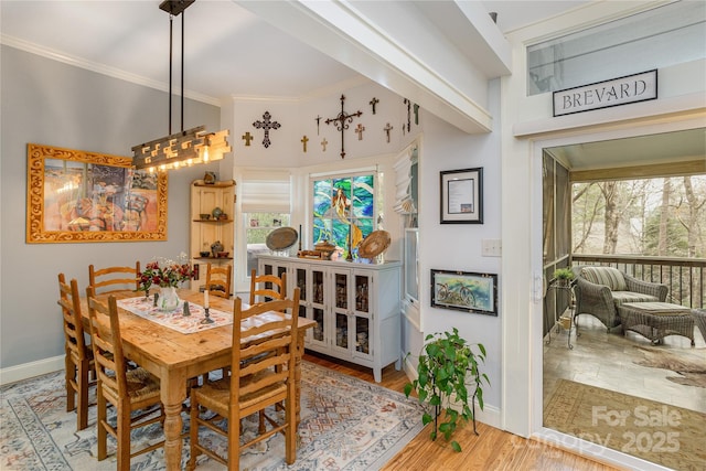 dining room with light wood finished floors, baseboards, and ornamental molding