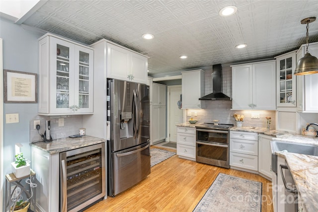 kitchen featuring a sink, an ornate ceiling, stainless steel appliances, wine cooler, and wall chimney exhaust hood