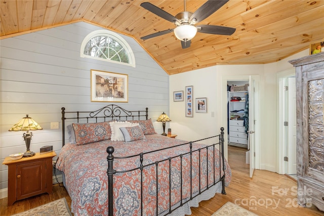 bedroom featuring a walk in closet, wood ceiling, lofted ceiling, wood finished floors, and a ceiling fan