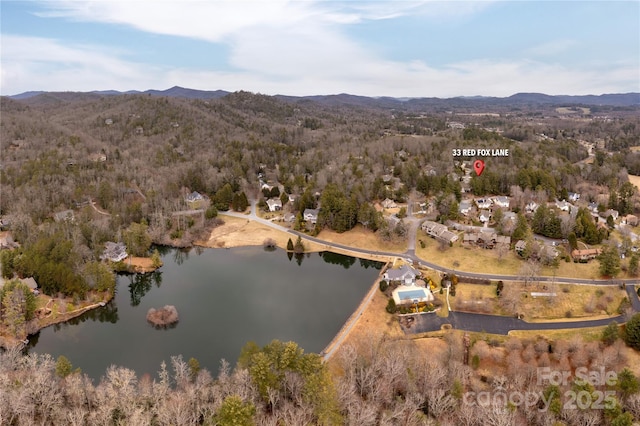 birds eye view of property featuring a wooded view and a water and mountain view