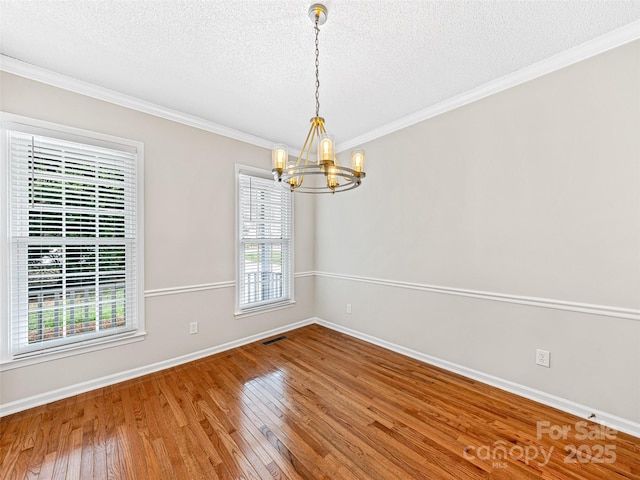 unfurnished room with hardwood / wood-style floors, an inviting chandelier, plenty of natural light, and visible vents